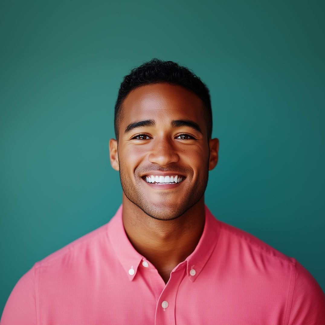 A man in a pink shirt is smiling for the camera