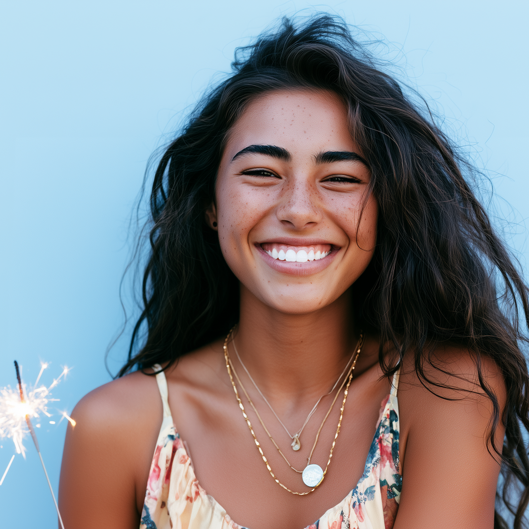 Smiling woman with long dark hair holding a sparkler against a light blue background