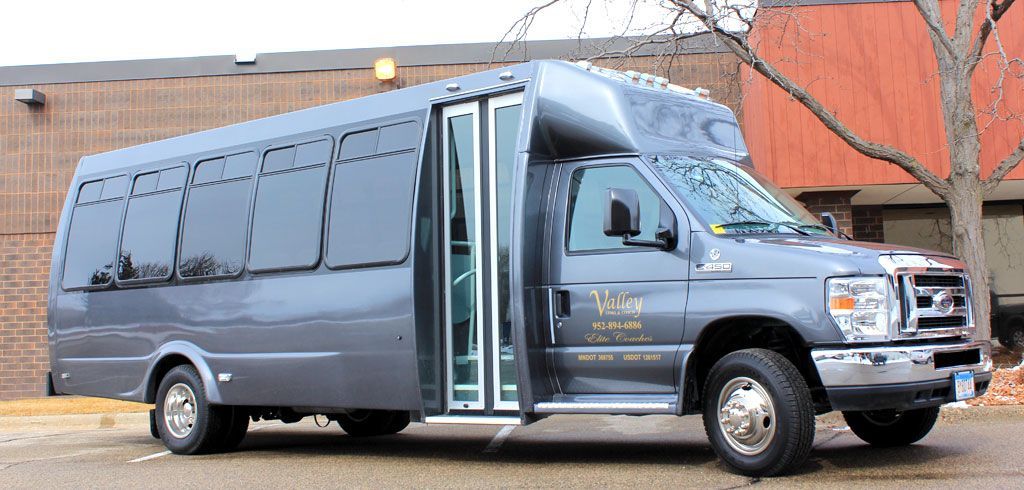 A gray bus is parked in front of a building.