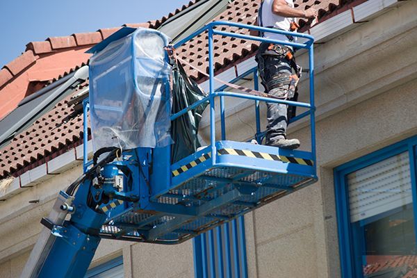Person on blue lift working on building exterior. Person on blue lift working on building exterior.