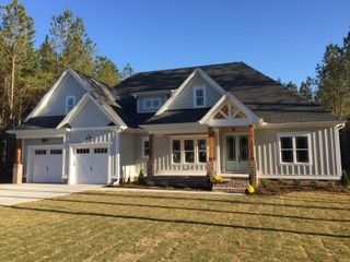 A light grey house with a black roof and two-car garage under a clear blue sky.