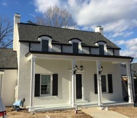 Close-up of a white building corner with dark grey gutters and soffit against a blue sky.