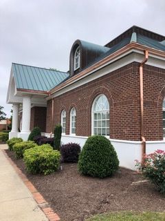 Dark gray rain gutter on a building's edge, against a cloudy sky. Dark gray rain gutter on a building's edge, against a cloudy sky.