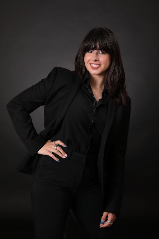 A woman is sitting at a desk with a laptop and a vase of flowers.