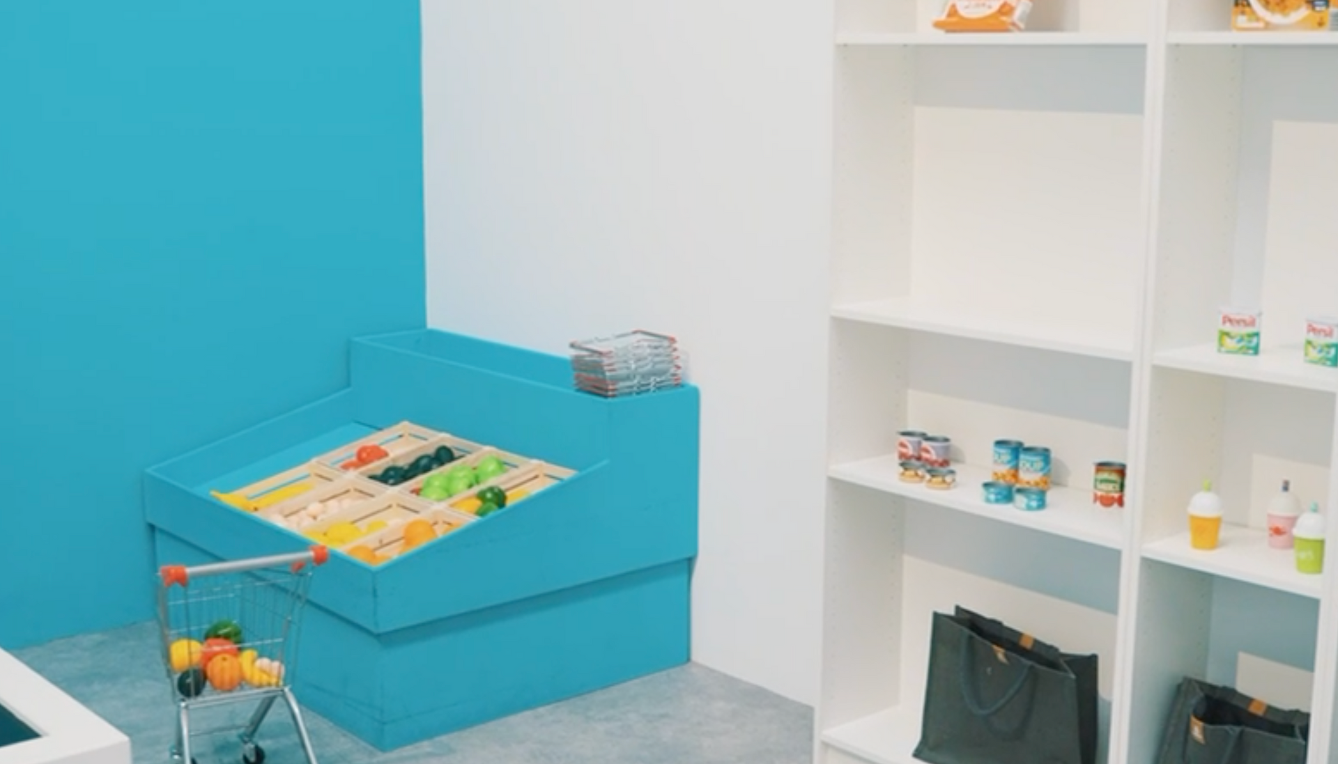 A room with a blue wall , white shelves , a toy cart and a sandbox.