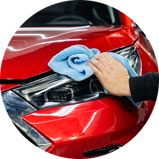 A person is cleaning a red car with a blue towel.