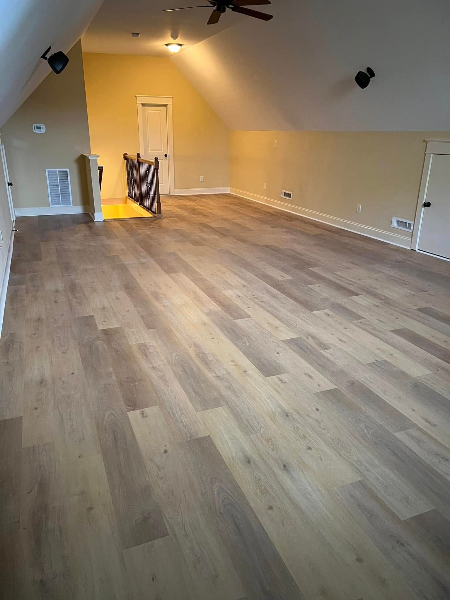 A large empty room with hardwood floors and a ceiling fan.