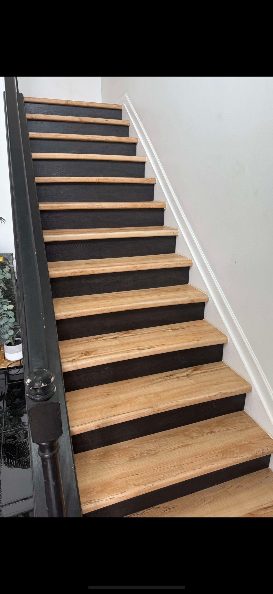 A staircase with wooden steps and black railing in a house.