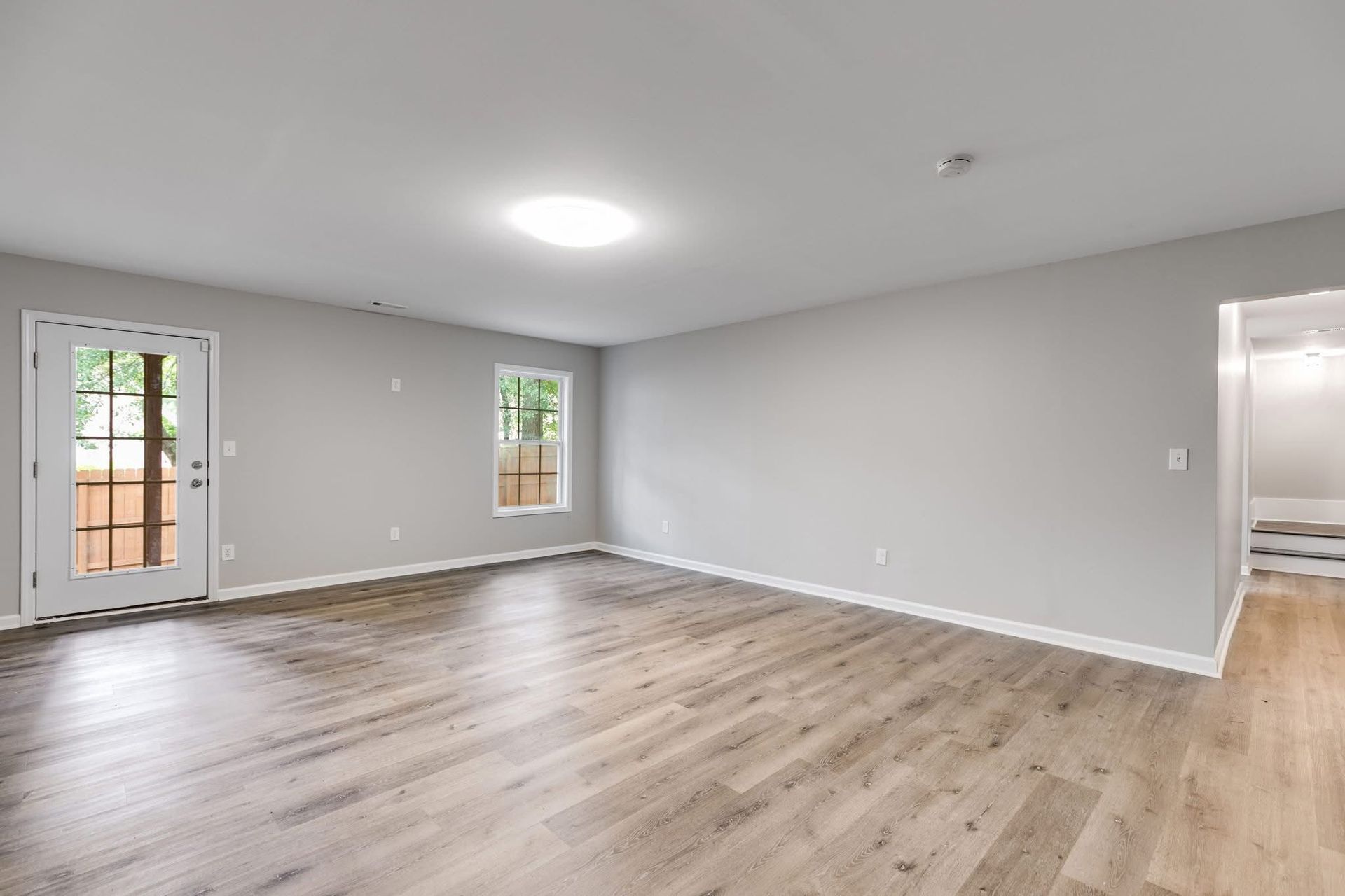 An empty living room with hardwood floors and gray walls.