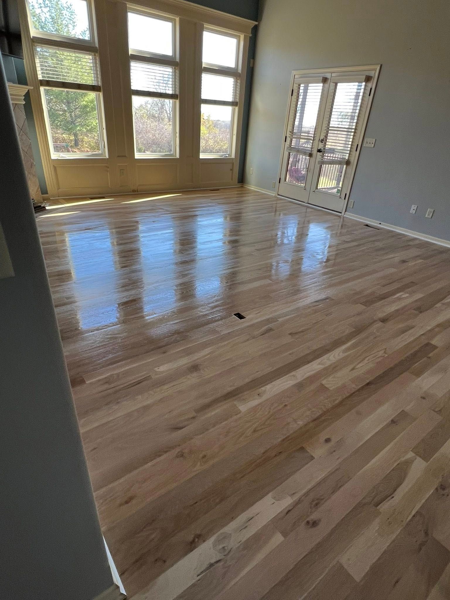A living room with hardwood floors and lots of windows.