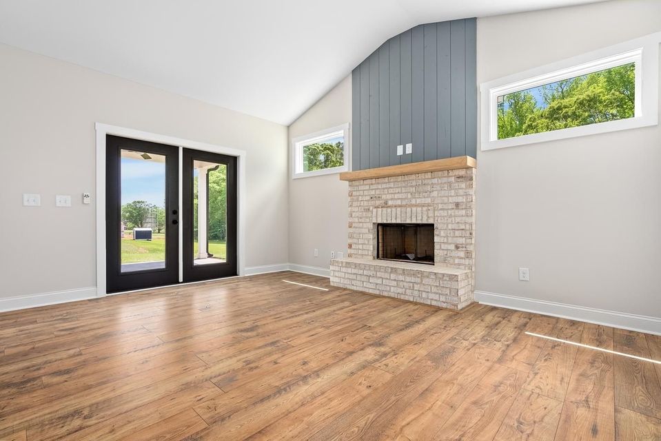 An empty living room with hardwood floors and a fireplace.