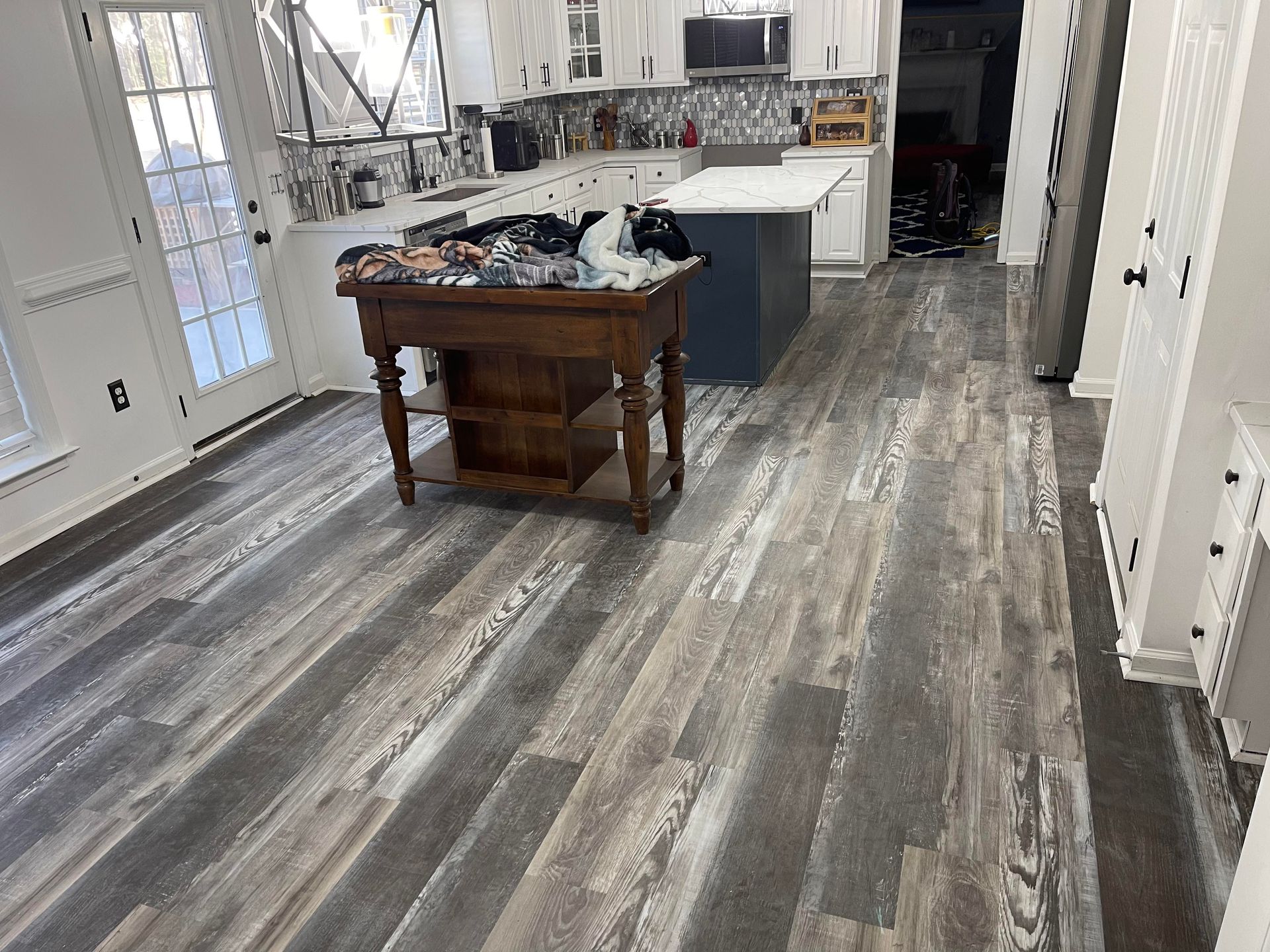 A kitchen with a wooden floor and a wooden table.