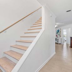 A staircase with wooden steps and a white railing in a house.