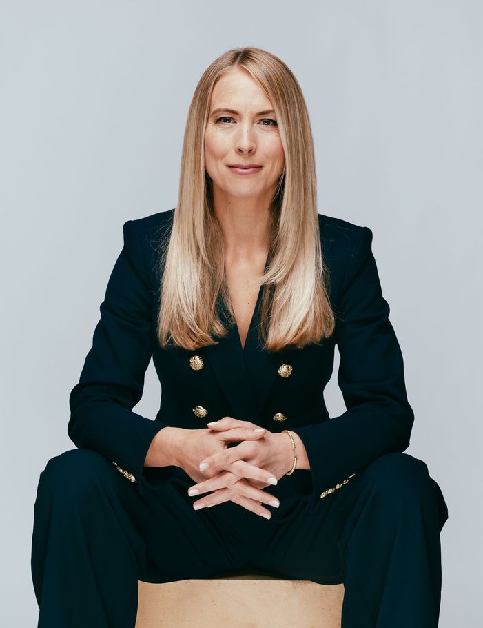 Sam Johnson in a suit is sitting on a box with her hands folded.