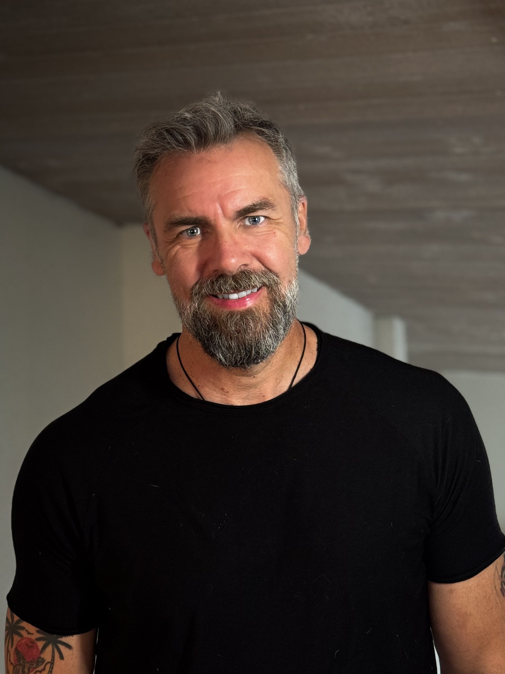A man with a beard wearing a black shirt and smiling.