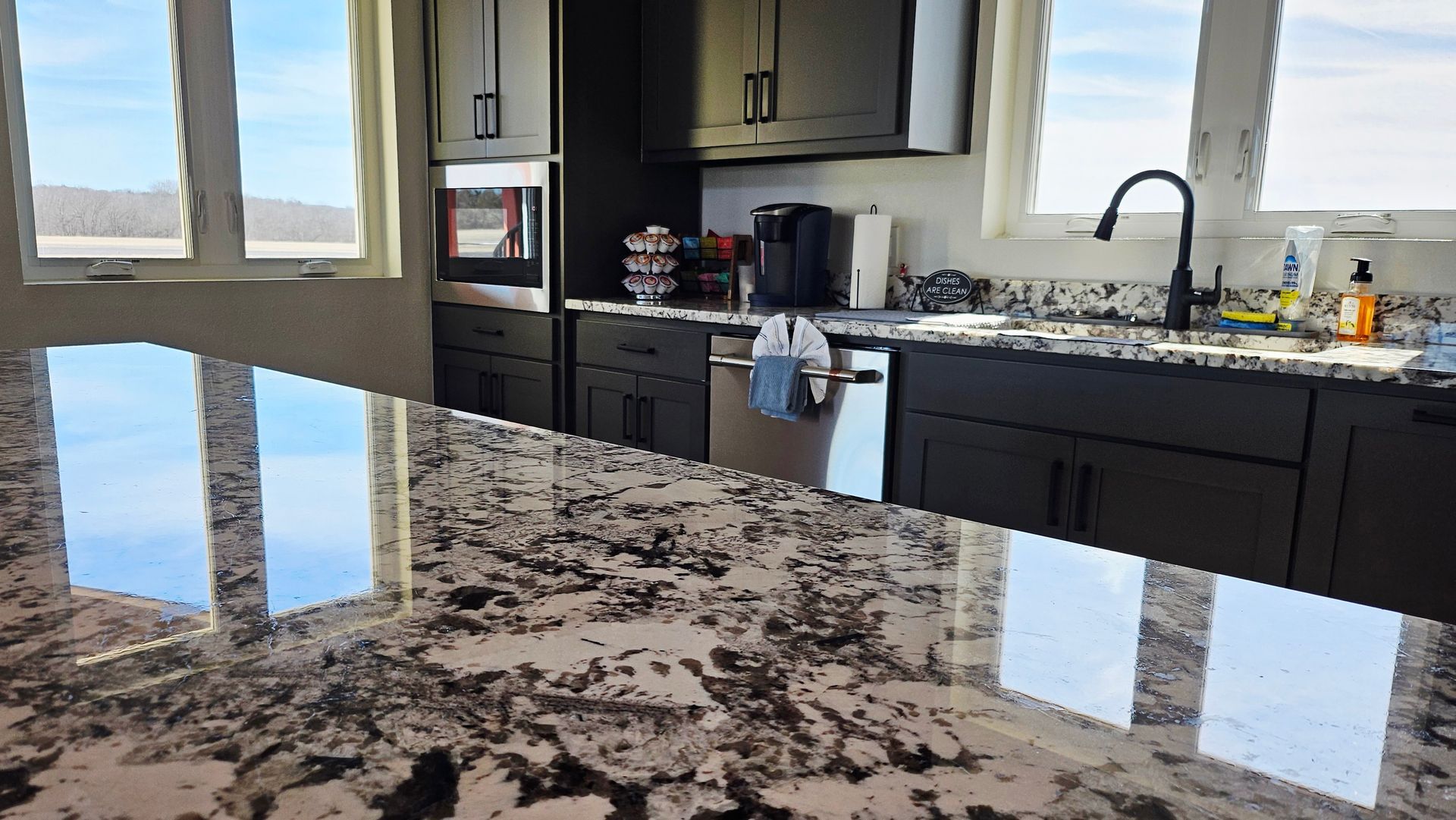Empty interior with concrete floor, large windows, and exposed beams. Scaffolding in the corner.