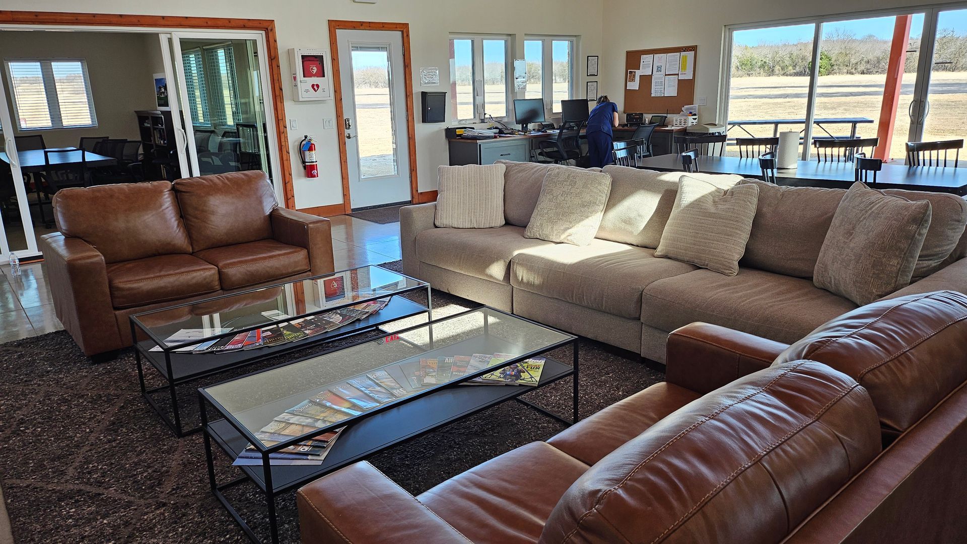 Empty dance studio with ballet barres, floor-to-ceiling mirror, and large windows.