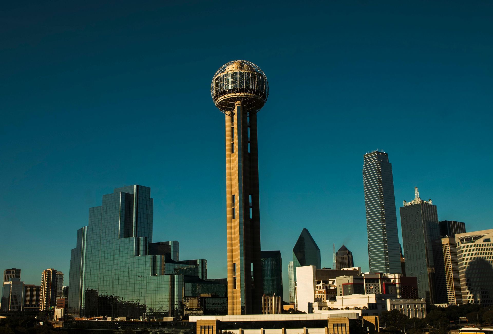 Dallas skyline with Reunion Tower prominent under a clear blue sky.