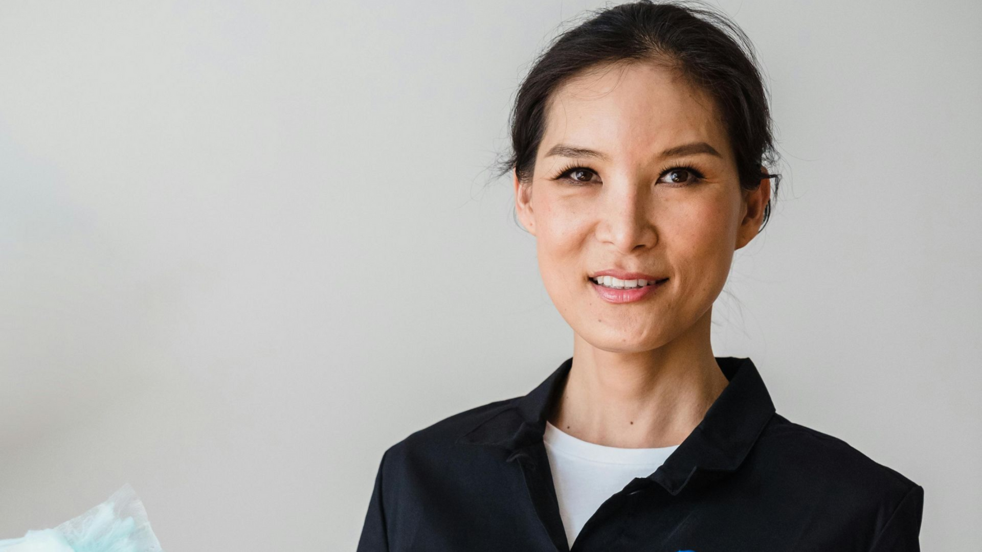 Woman in a black blazer smiles at the camera, a white background.