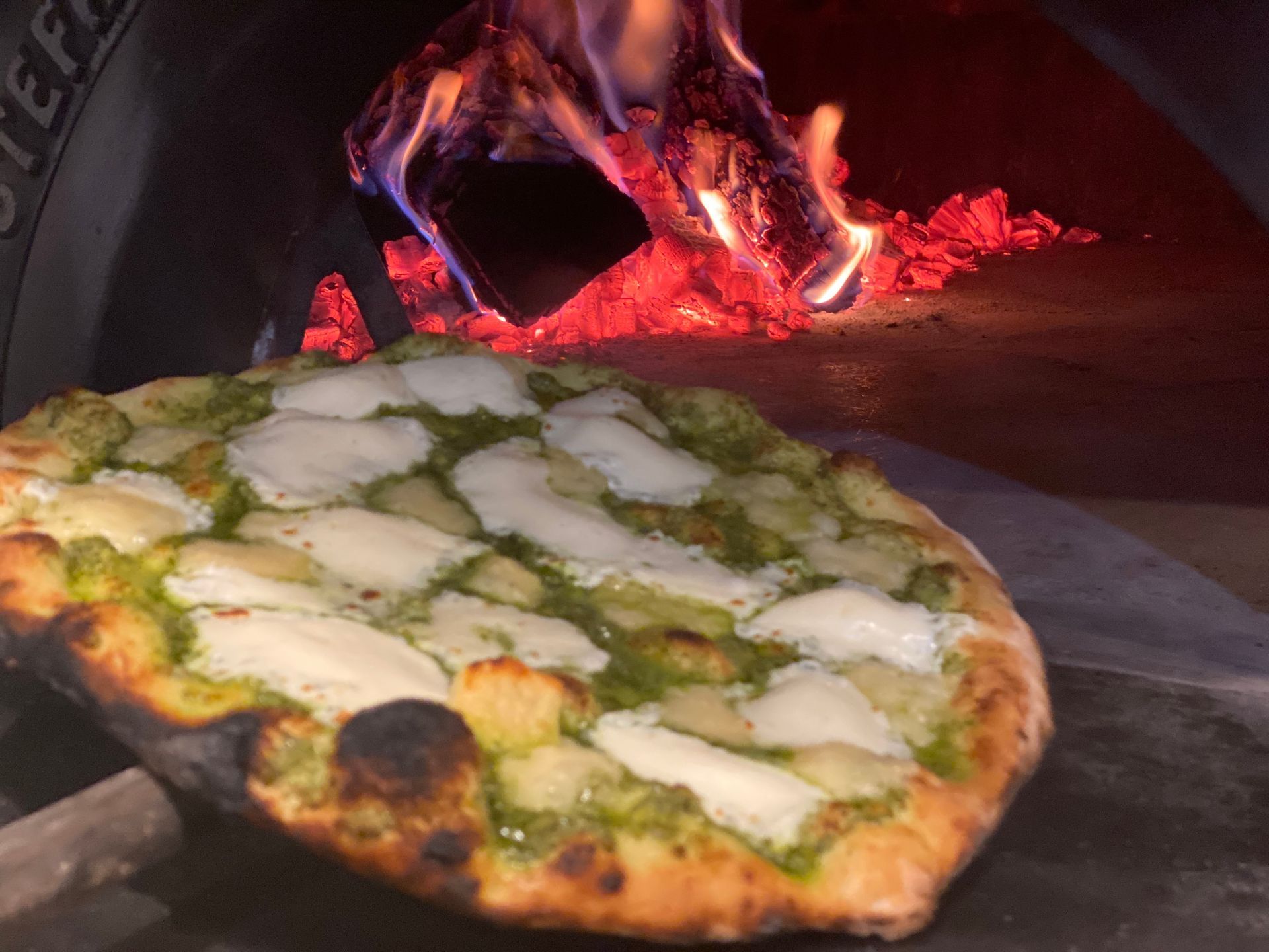 A pizza is being cooked in a wood fired oven