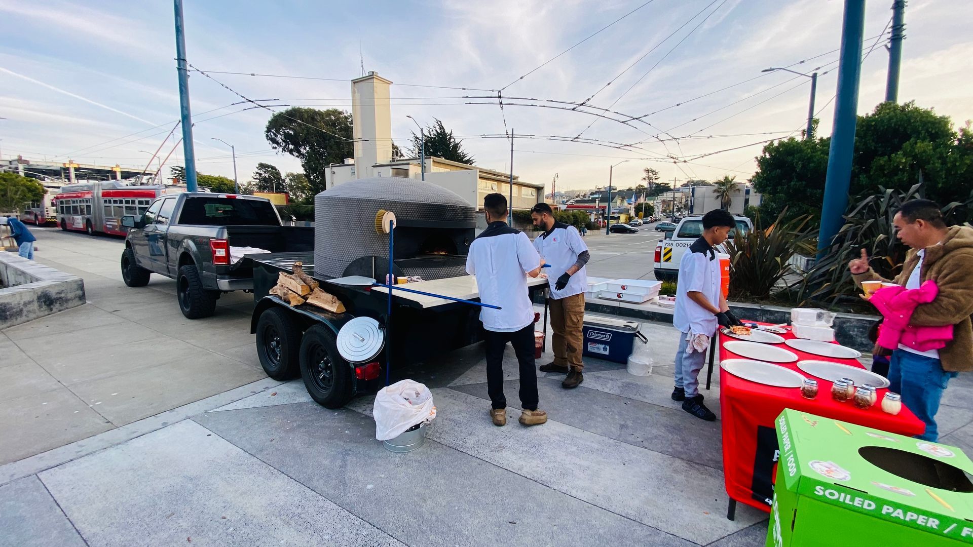 A group of people are standing in front of a pizza oven.