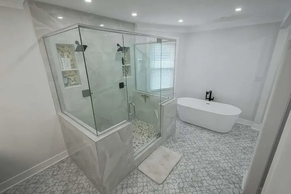 Bright modern bathroom with glass shower, freestanding tub, white walls, and mosaic tile floor