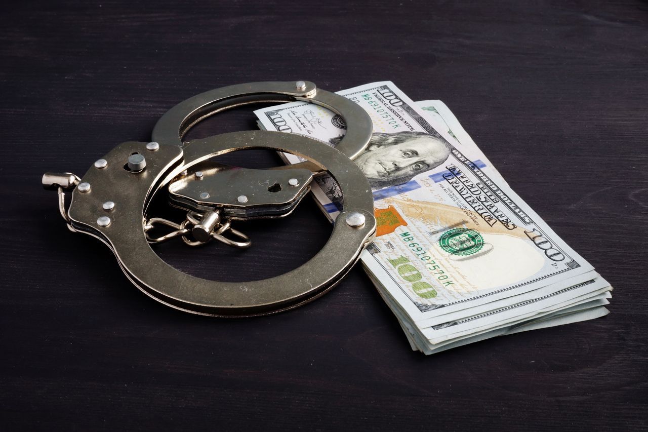 A pair of handcuffs sitting on top of a pile of money.