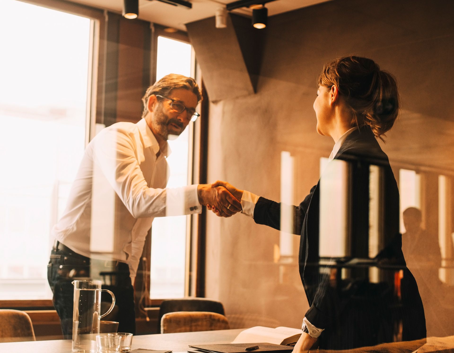 A man and a woman are shaking hands in a conference room.