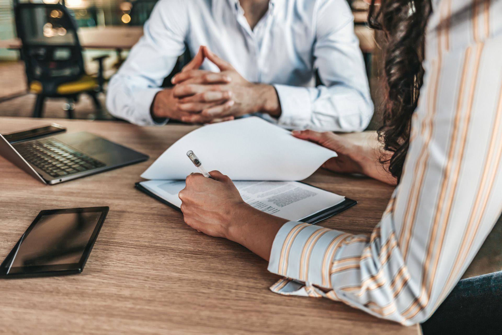 A man and a woman are sitting at a table with papers and a laptop.