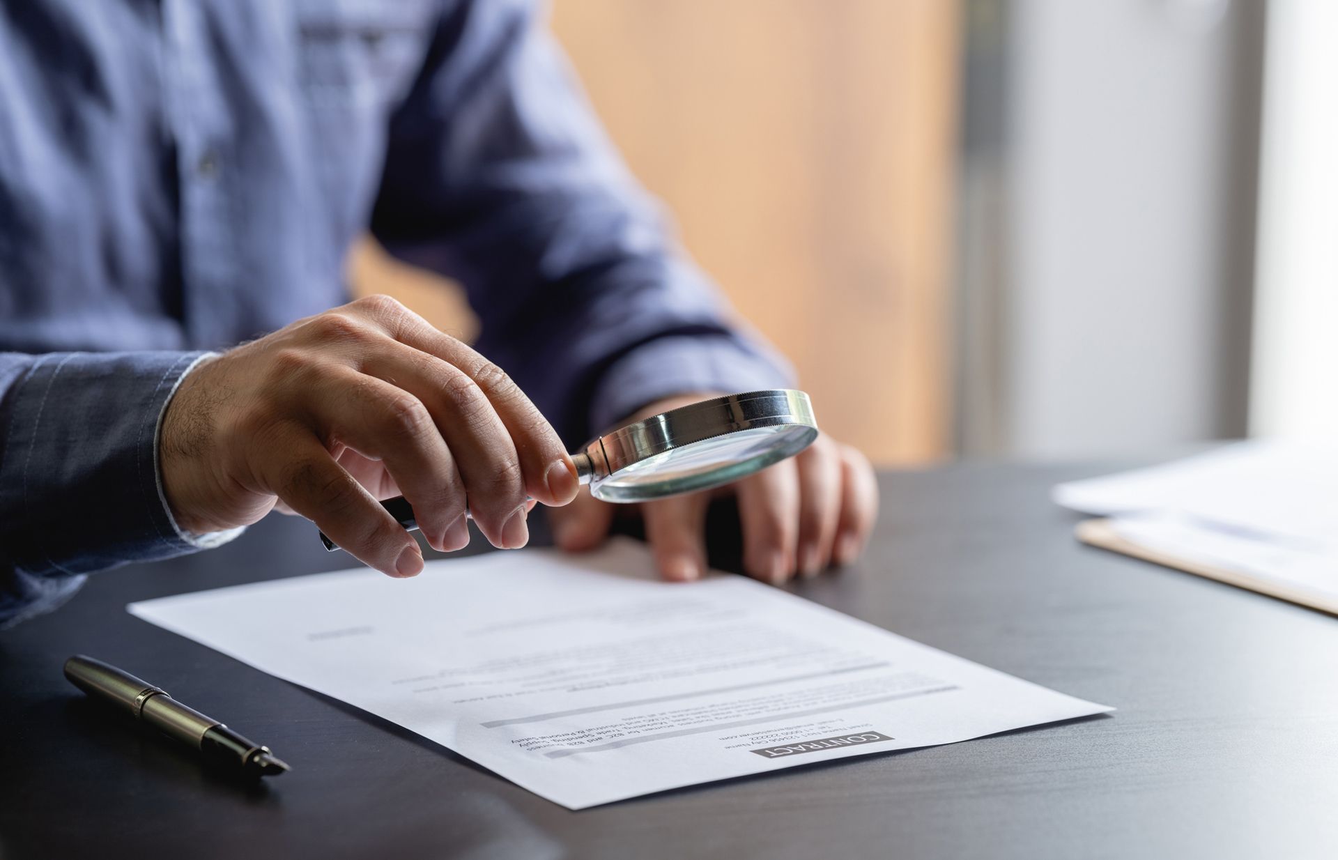 A man is using a magnifying glass to look at a piece of paper.