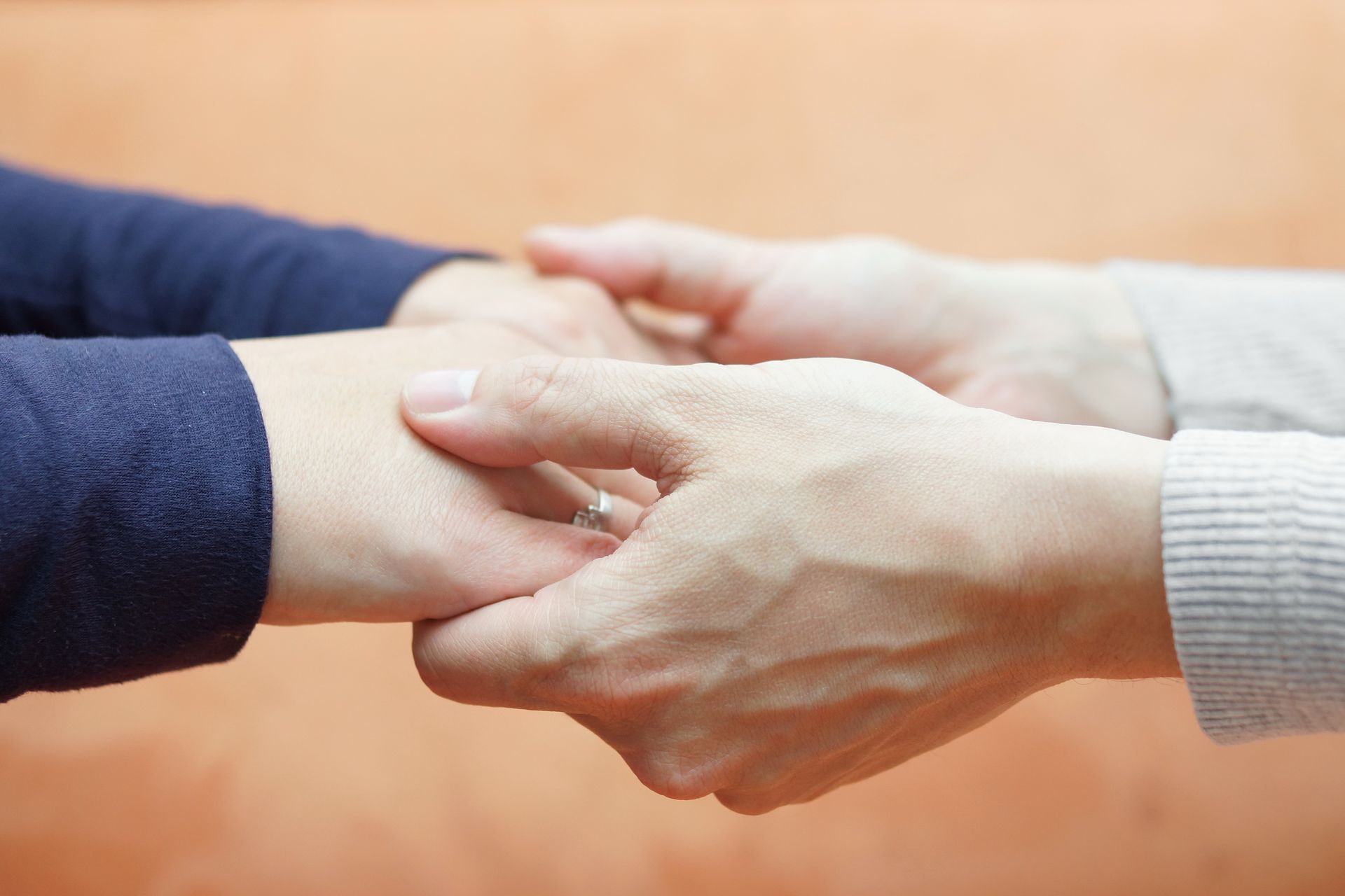 A woman is holding another woman 's hand with a ring on her finger.