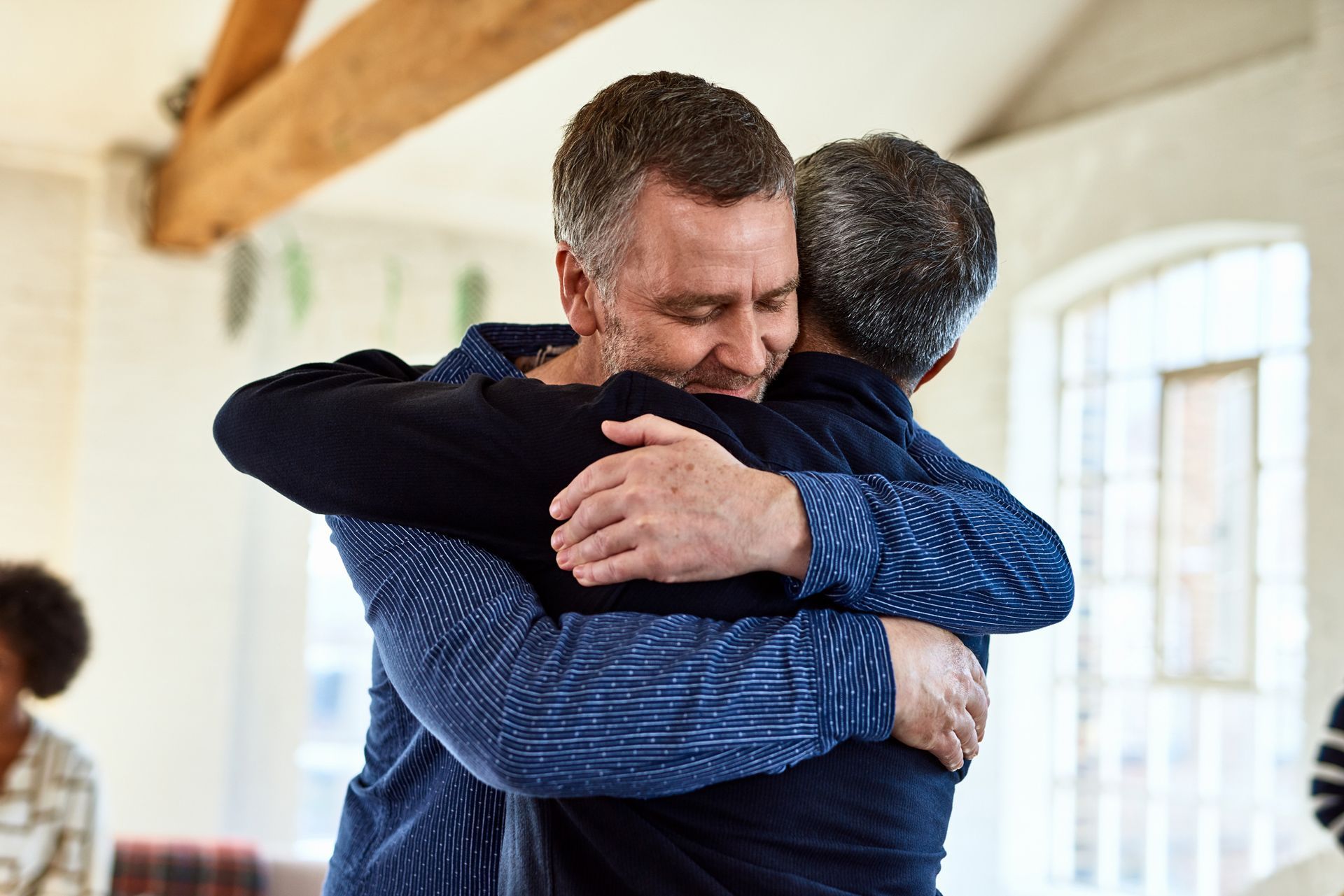 Two men are hugging each other in a room.