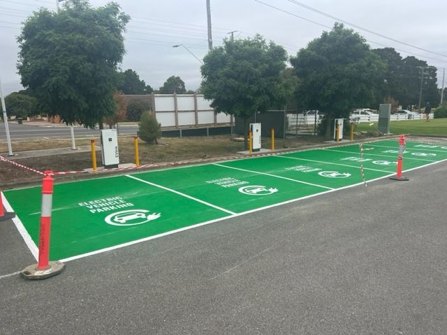 a green parking lot with a sign that says electric vehicle parking