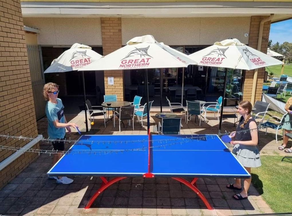 people playing ping pong under umbrellas that say great northern