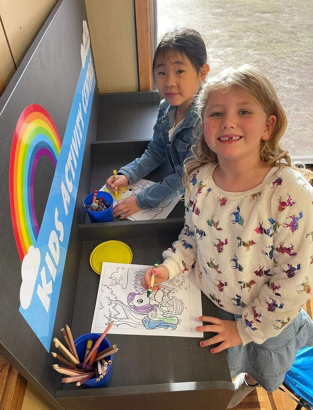 two little girls coloring in front of a kids activity center