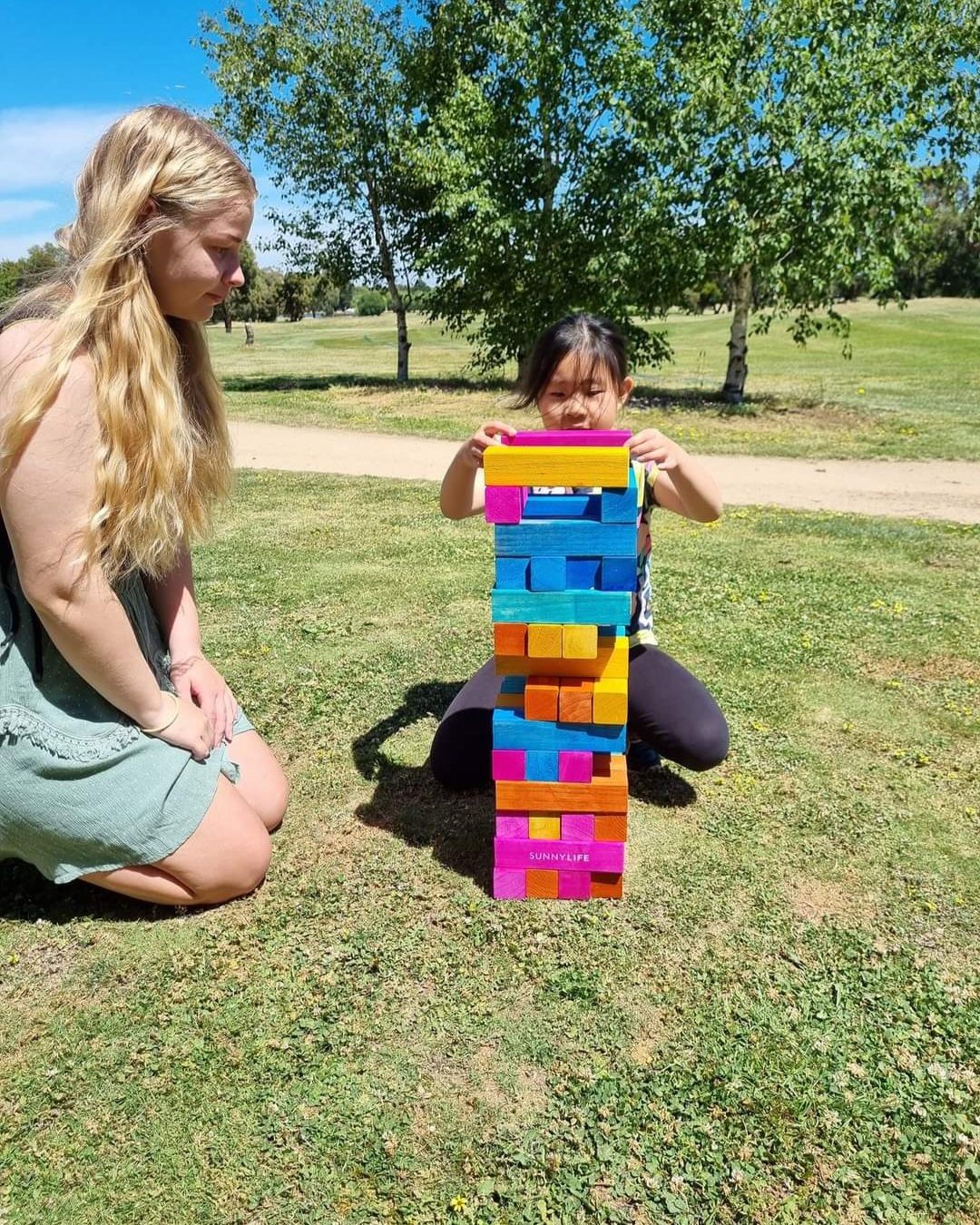 a woman and a little girl are playing a game of jenga