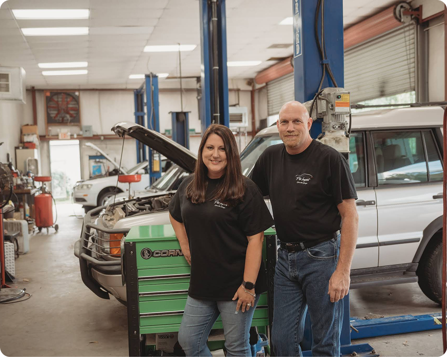A woman and man stand infront auto repair shop beside a green toolbox and vehicle. | Pro Import Automotive Service and Repair