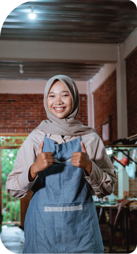 A woman wearing a hijab and an apron is giving a thumbs up.