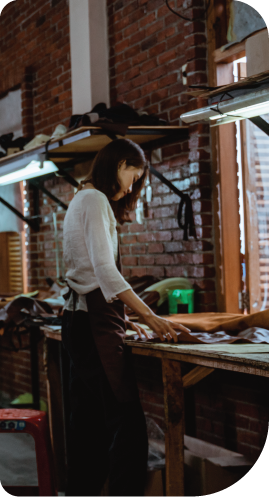A woman is working on a piece of leather in a workshop.