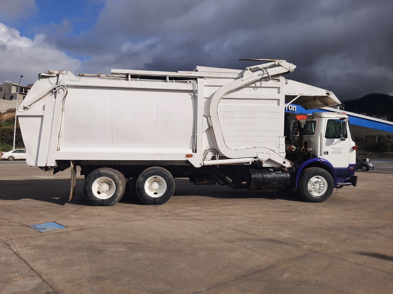 Un camión de basura blanco está estacionado en un estacionamiento.