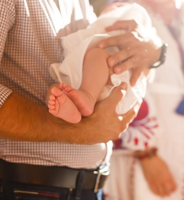 A Man is Holding a Baby in His Arms — Jimani Trophies & Engraving In Dapto, NSW