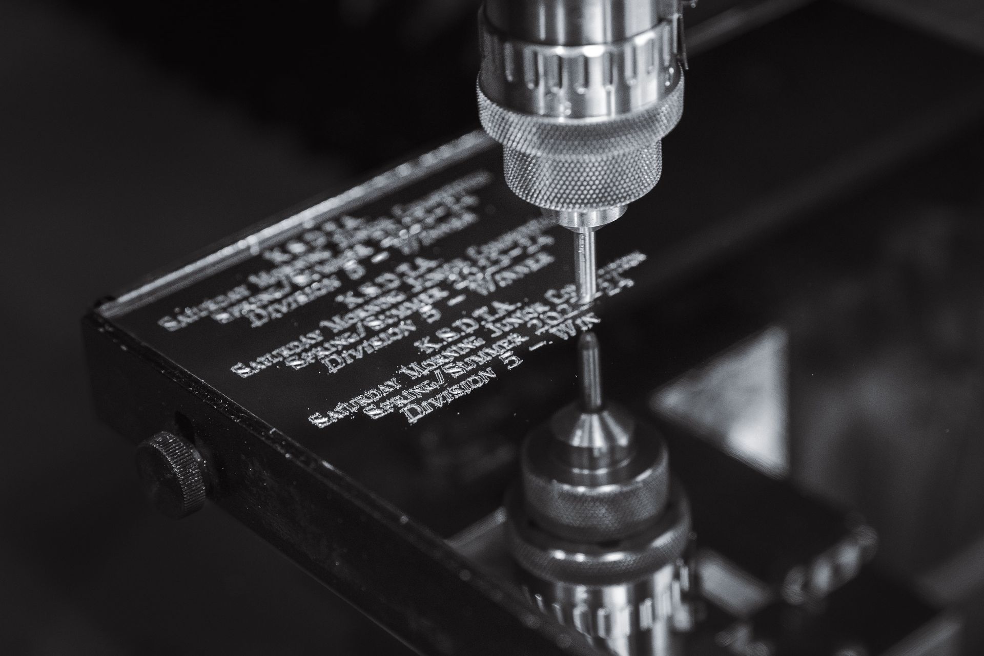 A Black and White Photo of a Machine Engraving a Piece of Metal — Jimani Trophies & Engraving In Dapto, NSW