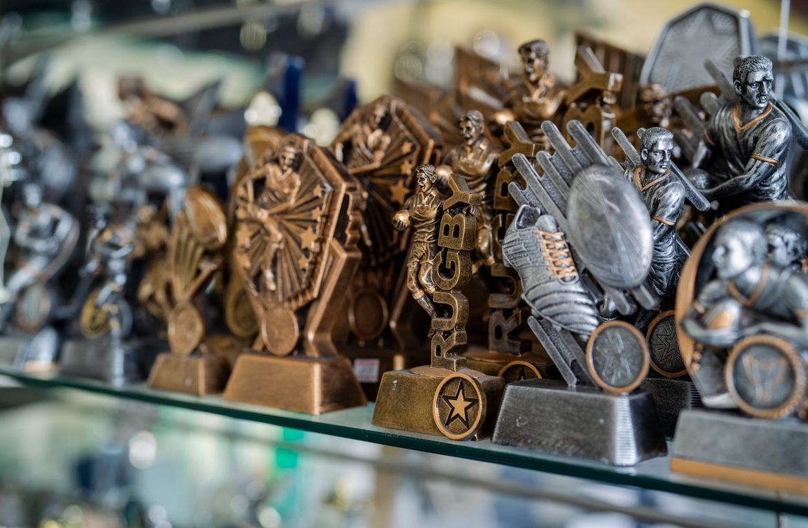 A Row of Trophies Are Sitting on a Glass Shelf — Jimani Trophies & Engraving In Dapto, NSW