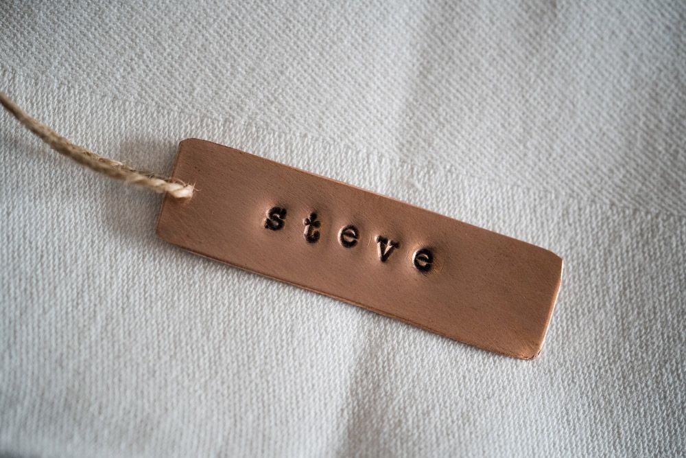 A Brown Tag with The Name Steve Written on It Is Sitting on A White Cloth — Jimani Trophies & Engraving in Dapto, NSW