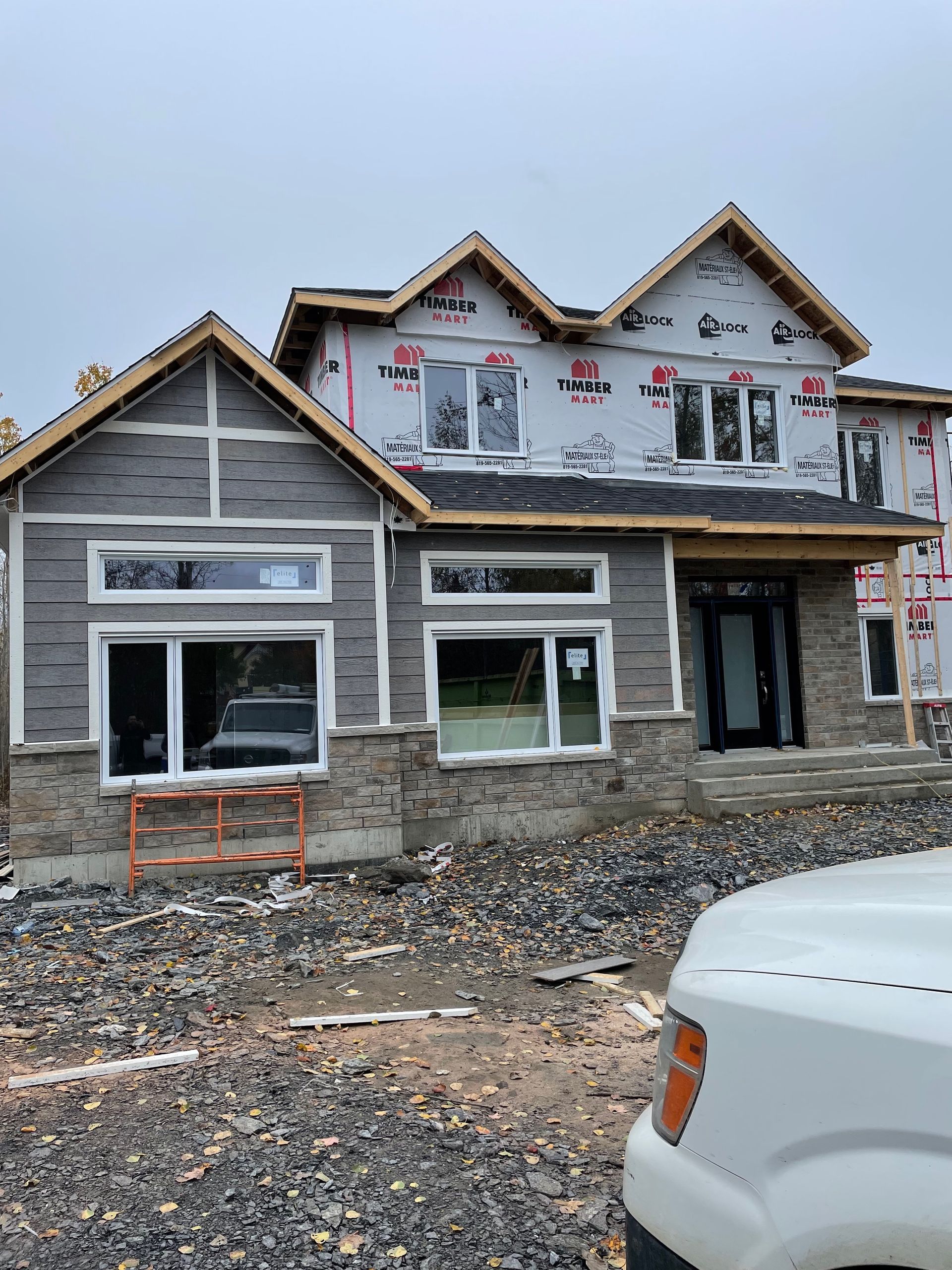 Un camion blanc est garé devant une maison en construction.