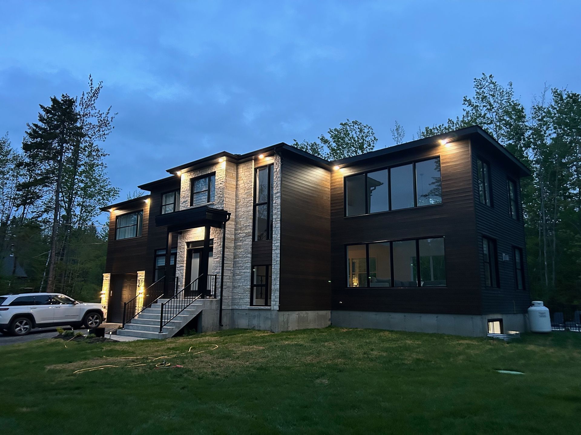 Une grande maison avec beaucoup de fenêtres est éclairée la nuit.