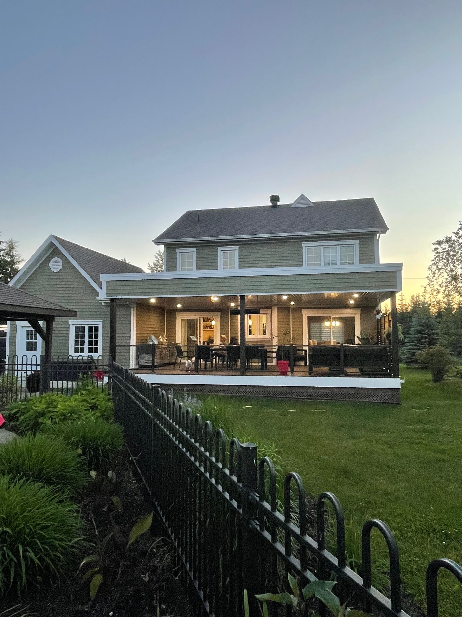 Une grande maison avec un grand porche et une clôture devant.