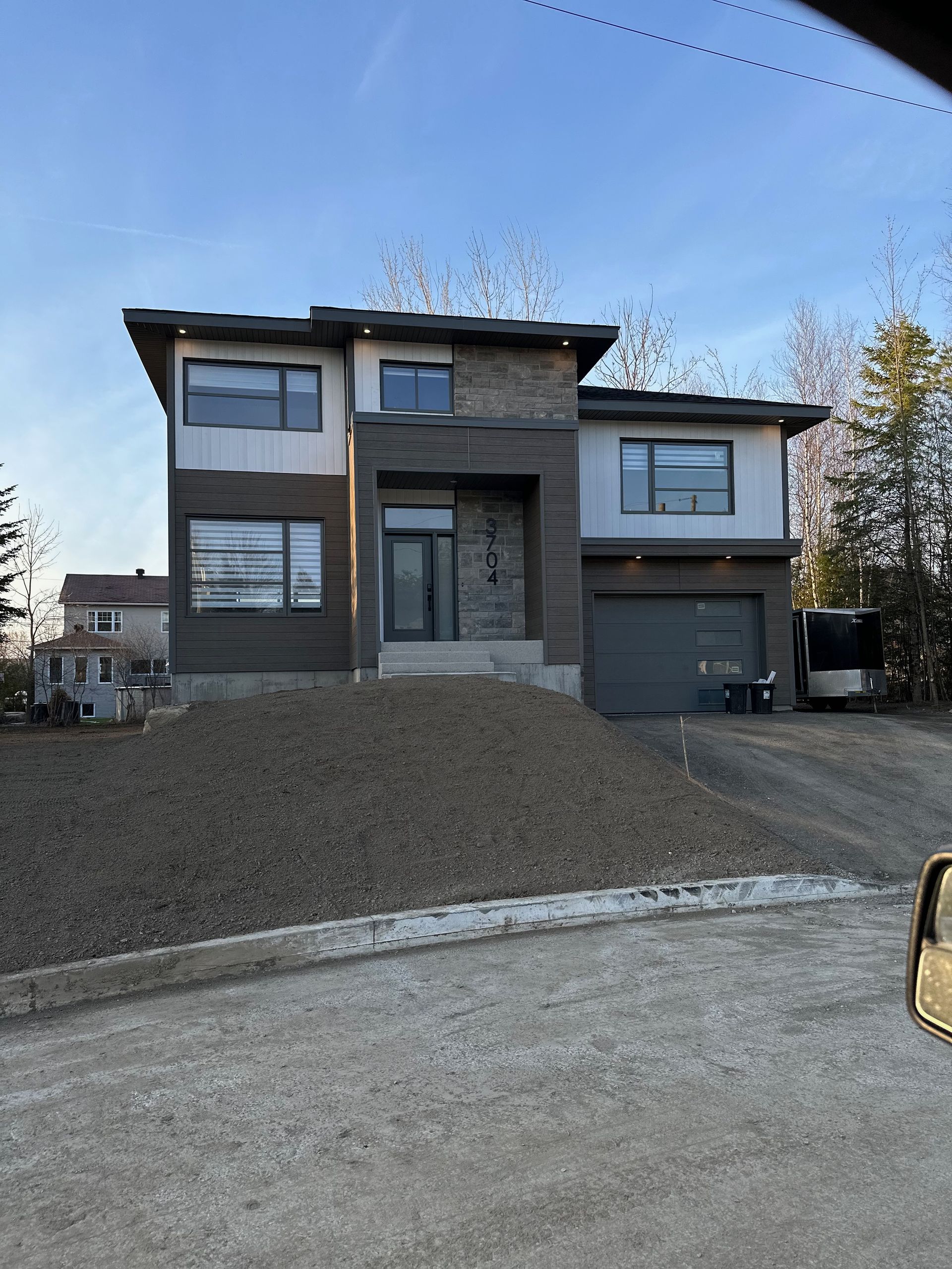 Une grande maison avec beaucoup de fenêtres est située au sommet d'une colline de terre.