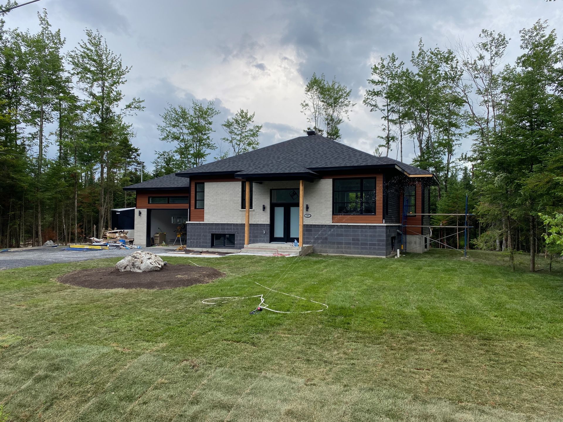 Une maison est située au milieu d'un champ verdoyant entouré d'arbres.