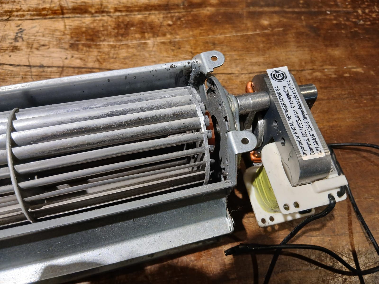 Un conjunto de ventilador de flujo cruzado sucio con un pequeño motor eléctrico acoplado,.